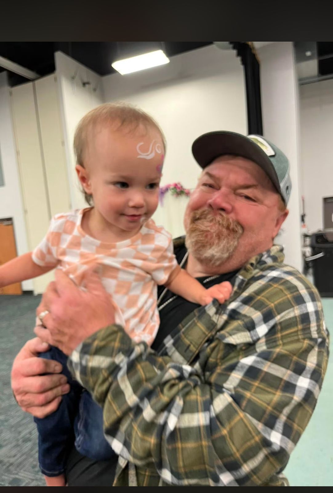 Neil in a green plaid shirt holding a toddler