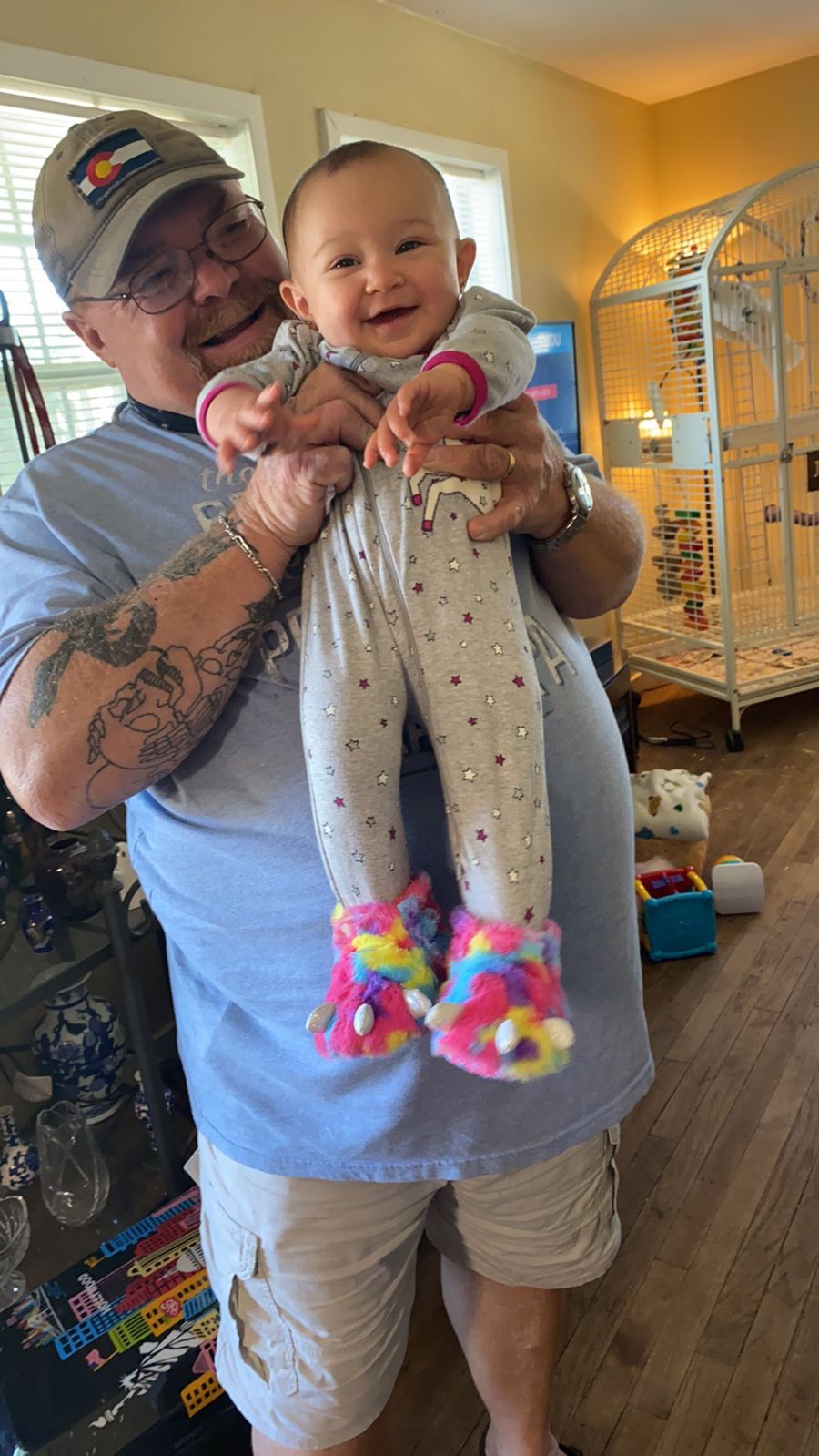 Neil smiling while holding a baby in pink shoes