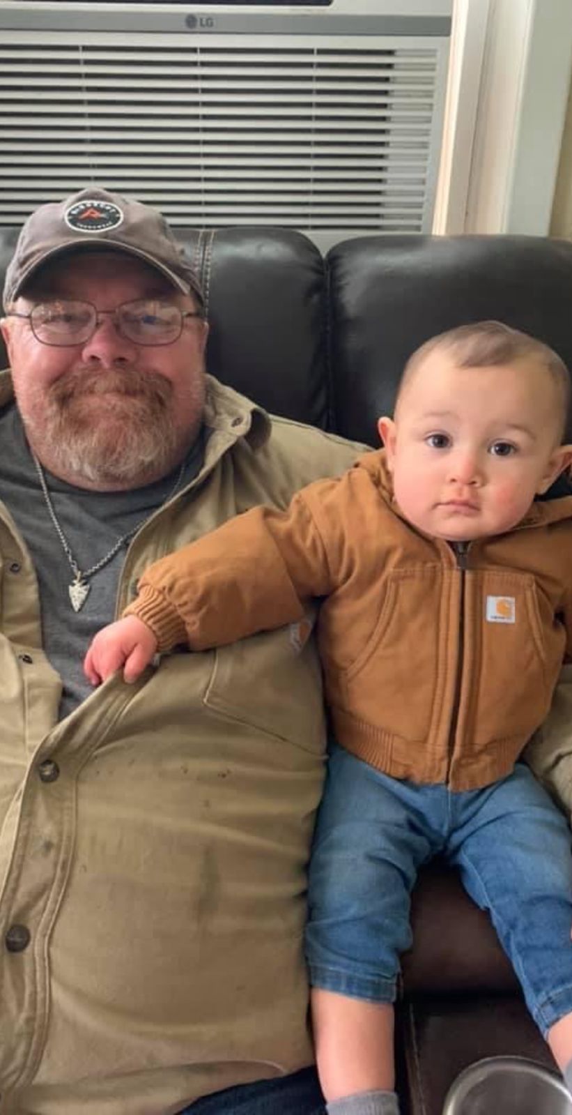 Neil in a camo hat on the couch with a young boy