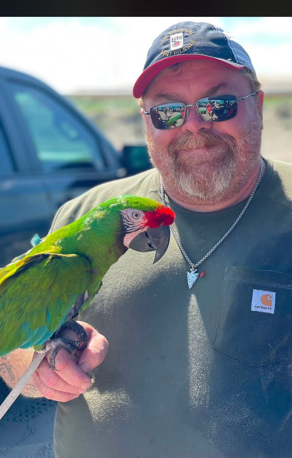 Neil with a green parrot perched on his arm