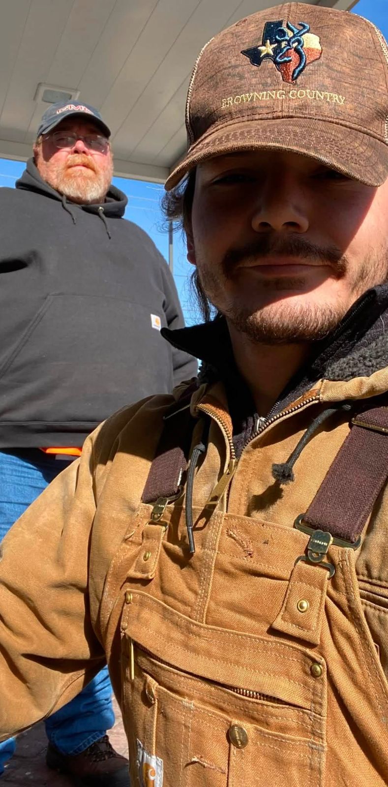 Selfie of Neil with a younger man in a camo hat