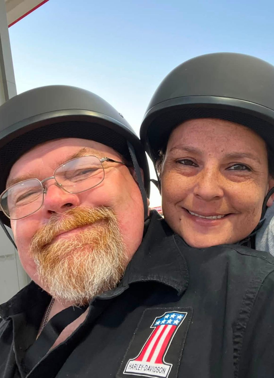 Neil and Jamie in motorcycle helmets, smiling