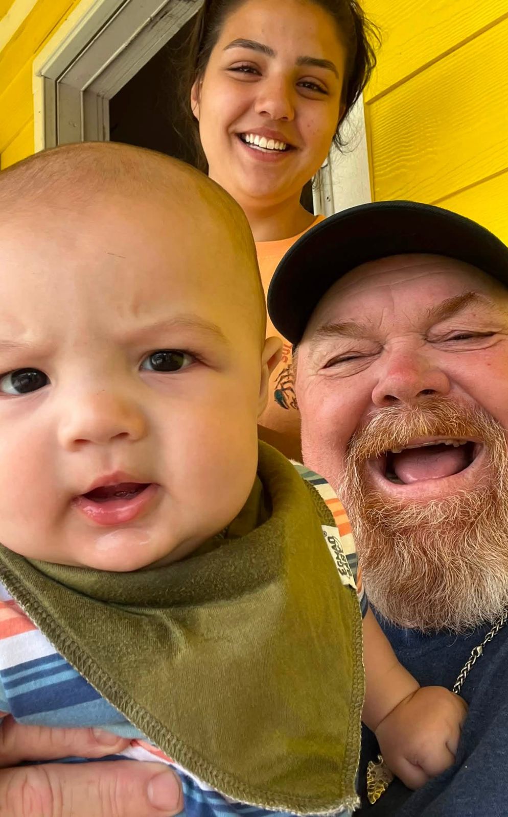 Neil and Jamie beside a baby in a high chair