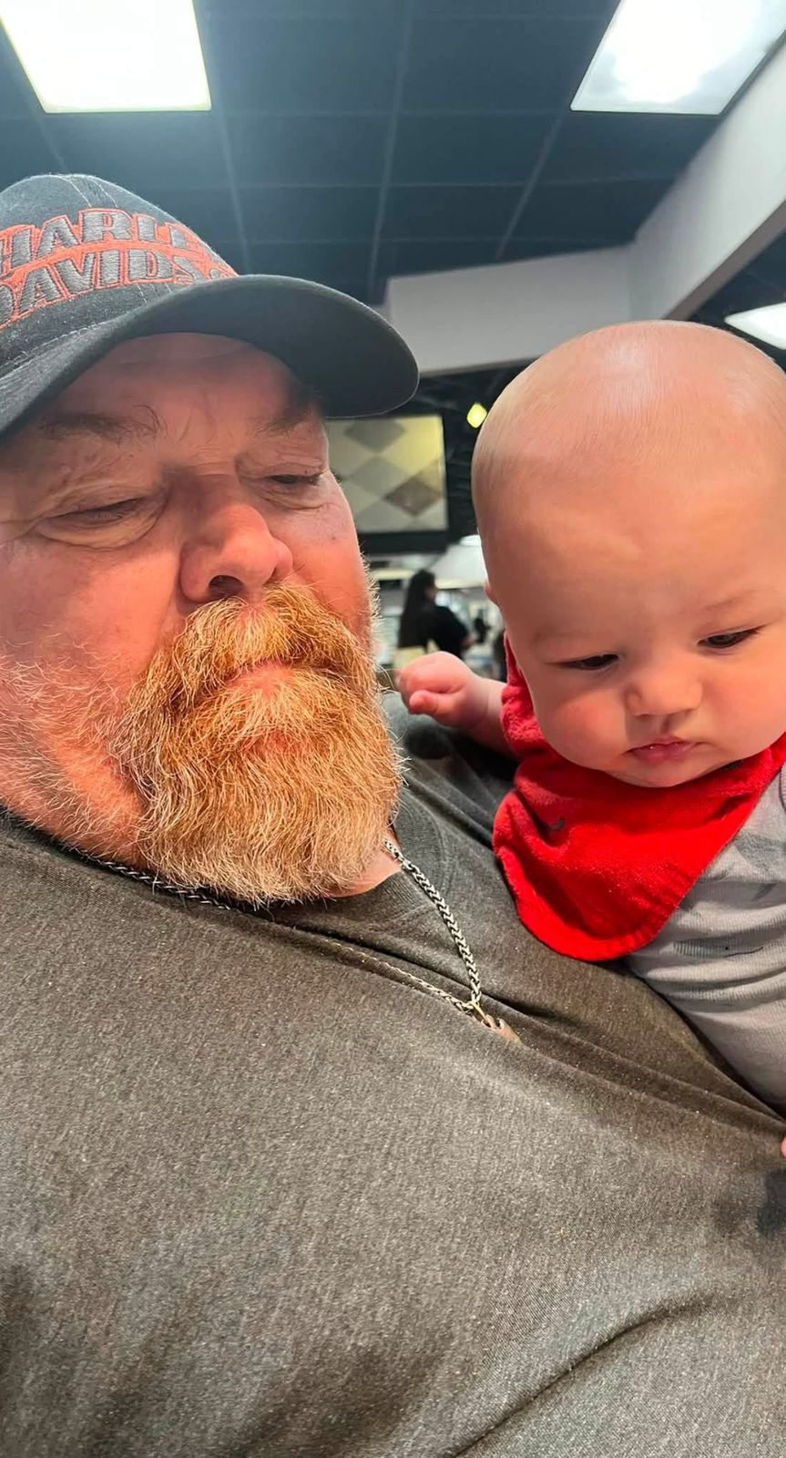 Neil smiling next to a baby in a red bib