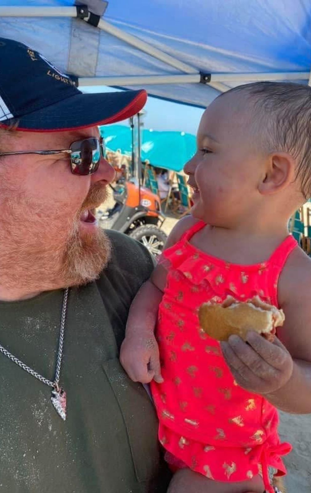 Neil at the beach with a toddler in a pink dress