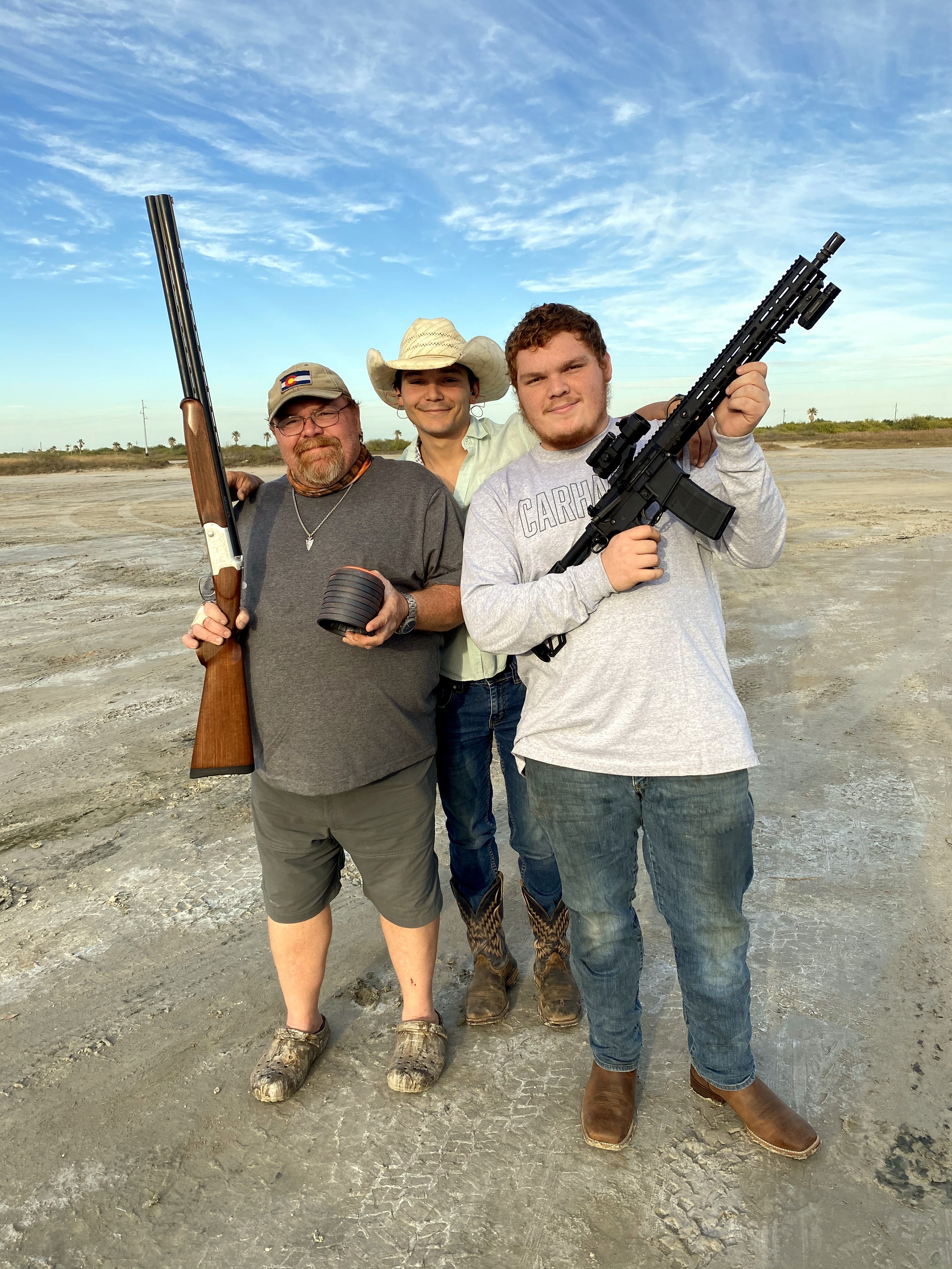Neil with two friends posing in an open sandy field