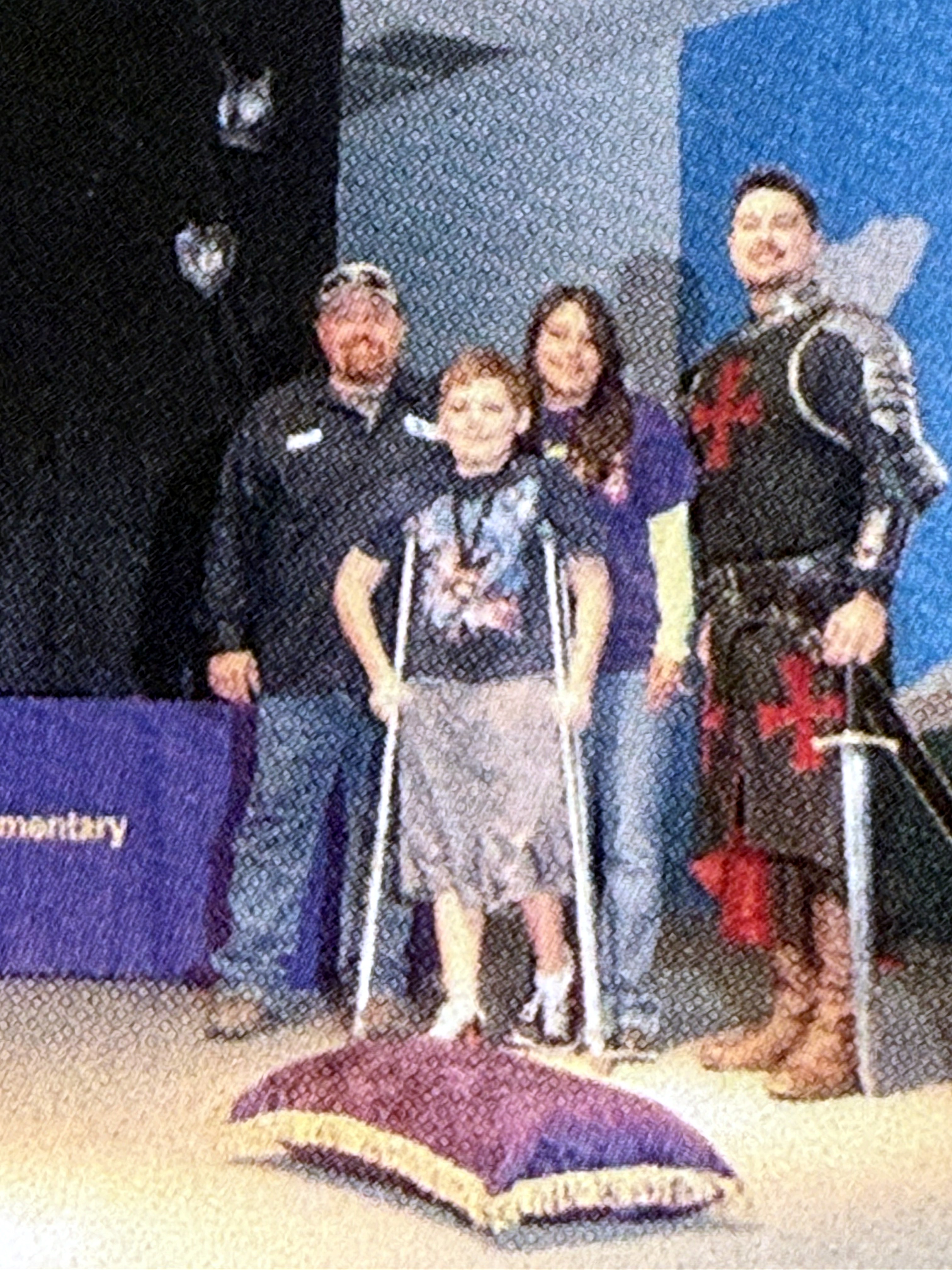 Young Neil on crutches with family and a knight at a school event