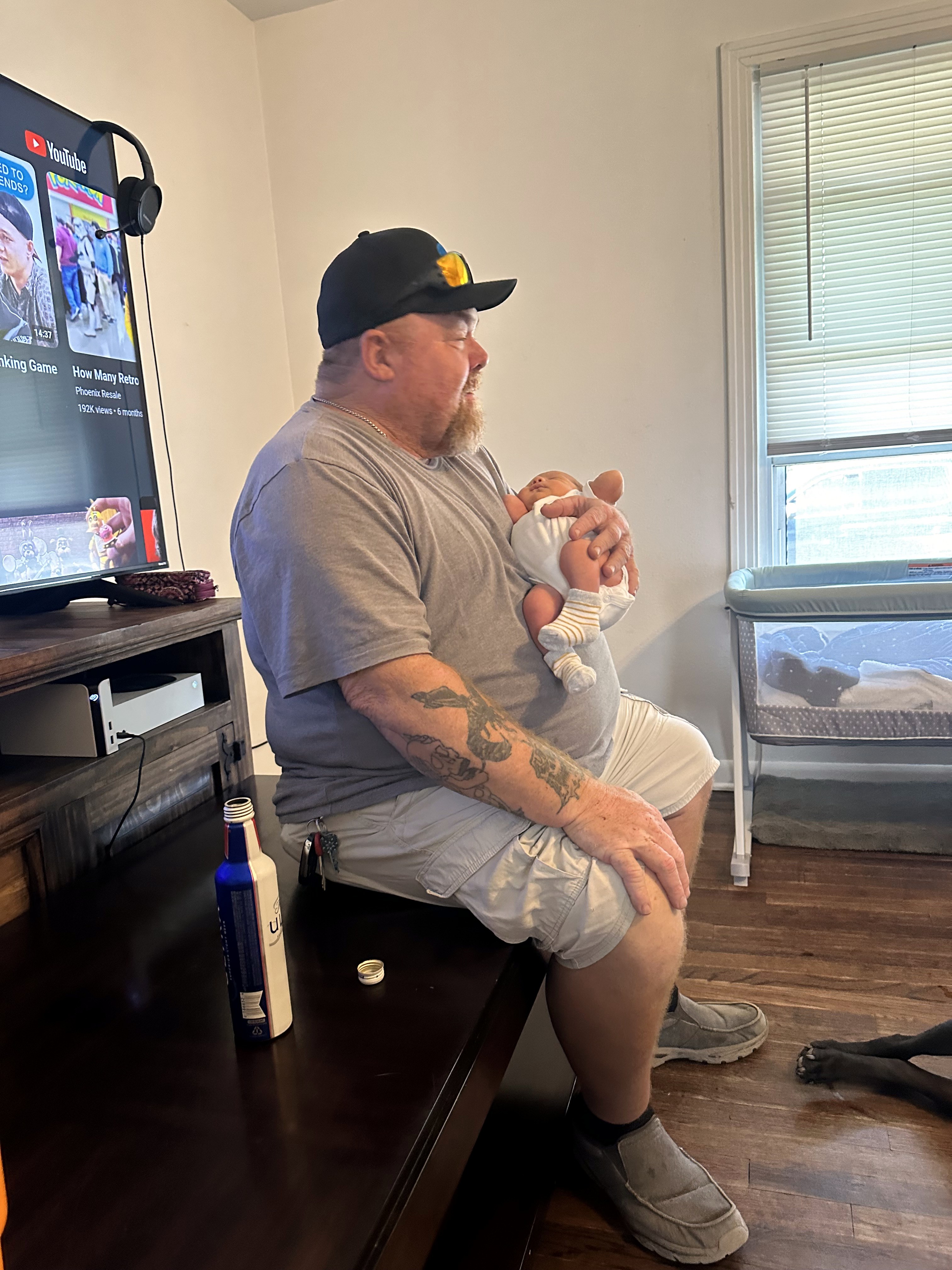Neil holding a newborn baby in a living room